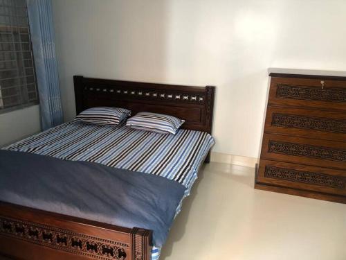 a bedroom with a bed with two pillows and a dresser at Home Away From Home in Chittagong