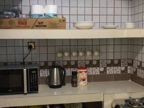 a kitchen counter with a microwave on a counter top at Home Away From Home in Chittagong