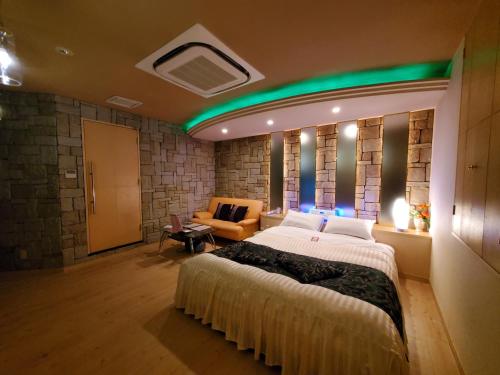 een slaapkamer met een groot bed en een bank bij ホテルセリーヌ(大人限定) in Asahikawa