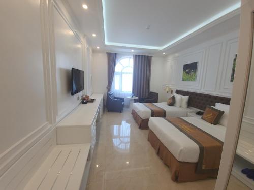 ハロンにあるNew Ha Long Hotel - by Bay Luxuryのベッド2台とテレビが備わるホテルルームです。