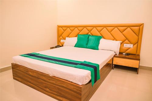 Bett mit einem Kopfteil aus Holz und grünen Kissen in der Unterkunft Hotel Green Apple in Rourkela