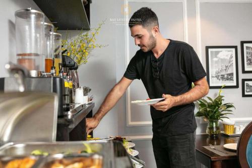 a man holding a plate in a kitchen at Maya boutique Hotel HN - by BAY LUXURY in Hanoi
