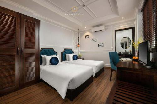 a bedroom with two beds and a desk and a television at Maya boutique Hotel HN - by BAY LUXURY in Hanoi