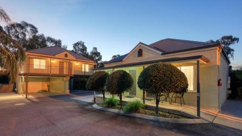 a house with trees in front of it at Bridges on Meninya Motel & Apartments in Moama