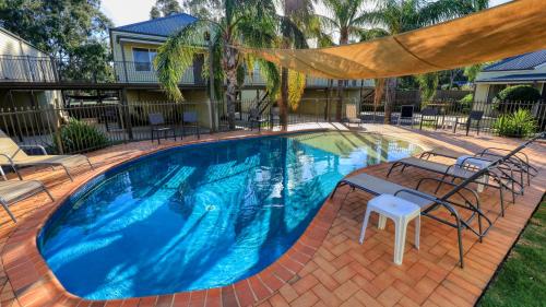 a large swimming pool with chairs and a table at Bridges on Meninya Motel & Apartments in Moama