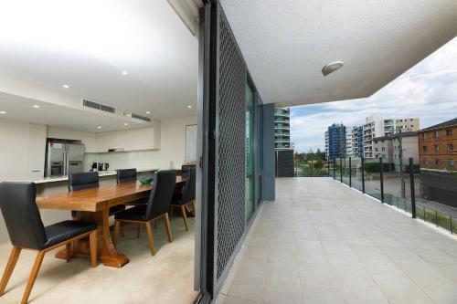 a dining room with a table and chairs on a balcony at The Strand 303 in Forster