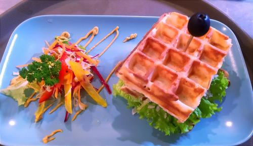 un sándwich de gofre y una ensalada en un plato azul en Colours of Life Home, en Weligama