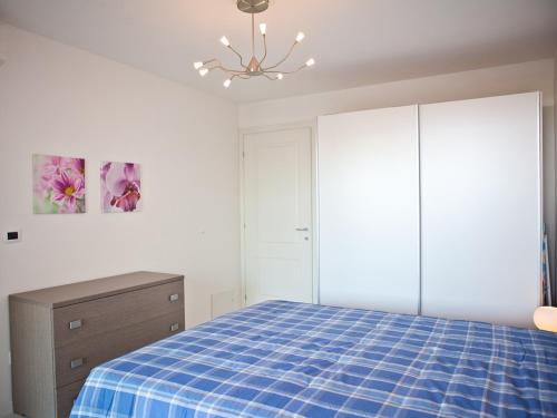 1 dormitorio con 1 cama, vestidor y lámpara de araña en Costa Azzurra Residence en Grado