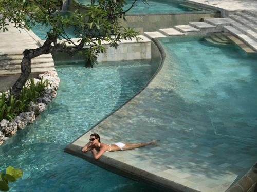 a woman laying in a swimming pool at AYANA Segara Bali in Jimbaran