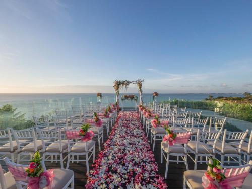 a row of white chairs with flowers on them at AYANA Segara Bali in Jimbaran