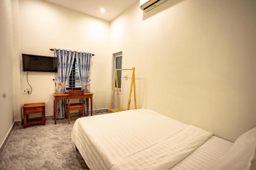 a white bedroom with a bed and a desk at Hoa ban Homestay in Hue