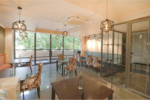 a dining room with tables and chairs and windows at Oriva Shanit in New Delhi