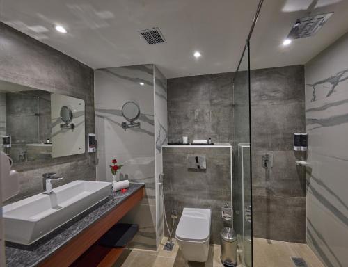 a bathroom with a sink and a toilet and a shower at Golden Tulip Tirupati in Tirupati