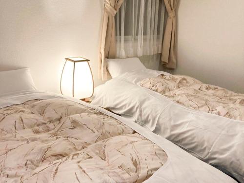 an unmade bed in a bedroom with a lamp at Pension Todoroki in Atami