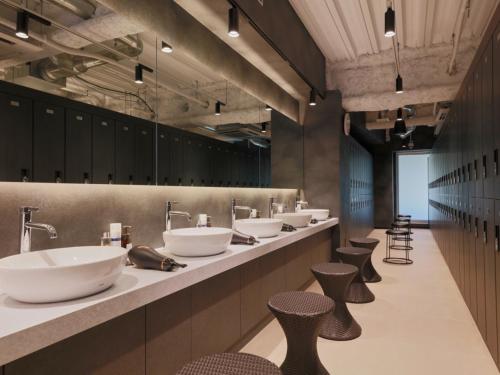 una fila de lavabos y taburetes en un baño público en Rembrandt Cabin & Spa Shimbashi - Caters to Men, en Tokio
