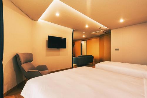 a hotel room with a bed and a chair and a tv at Kwangsu Hotel Haeundae in Busan