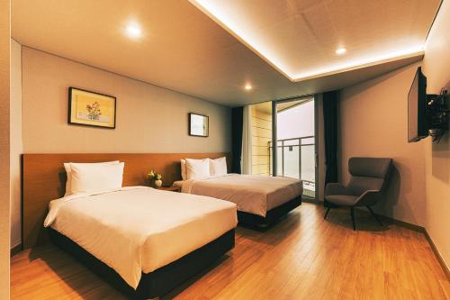 a hotel room with two beds and a chair at Kwangsu Hotel Haeundae in Busan