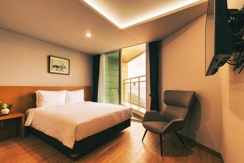 a bedroom with a bed and a chair and a window at Kwangsu Hotel Haeundae in Busan