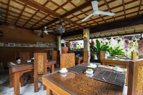 a restaurant with wooden tables and chairs and a ceiling at Amoya Inn in Ubud