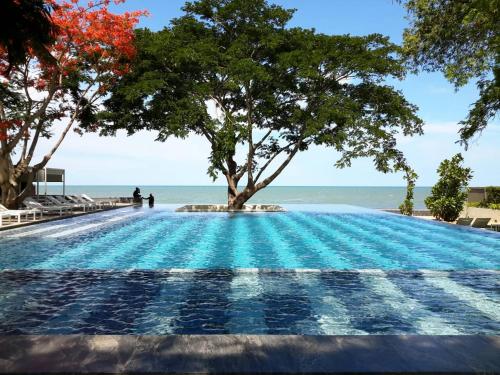 a swimming pool with a tree on the beach at บ้านแสนคราม ห้องติดสระ Baan San Kraam HUA HIN Family Room - Pool Access in Phetchaburi