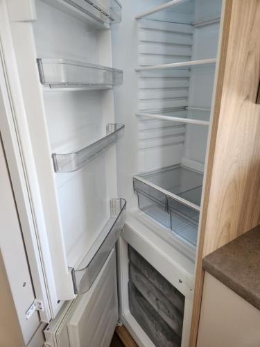 um frigorífico branco com prateleiras vazias numa cozinha em 4 BEDROOMS CARAVAN at Waterside Leisure Holiday Park em Skegness