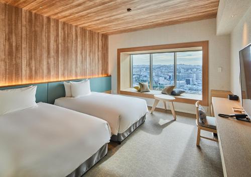 a hotel room with two beds and a window at HOTEL AlaCOOJU OKINAWA in Urasoe