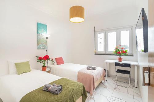 1 dormitorio con 2 camas, escritorio y ventana en Happy Holiday Cascais - Home, en Cascais