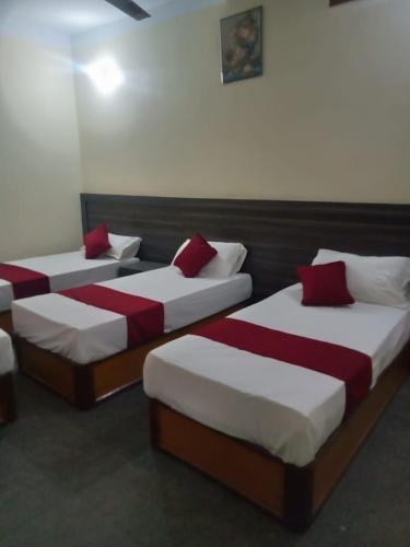 three beds with red pillows in a room at HOTEL STAR HOLIDAY PVT LTD in Bhairāhawā