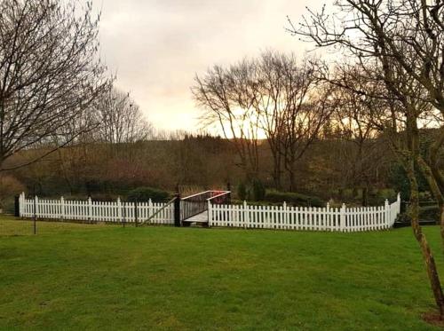 a white picket fence in a field with grass at L'orée du bois in Roy