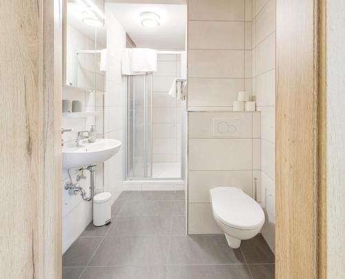 ein weißes Bad mit einem WC und einem Waschbecken in der Unterkunft Weisses Rössl in Pfreimd