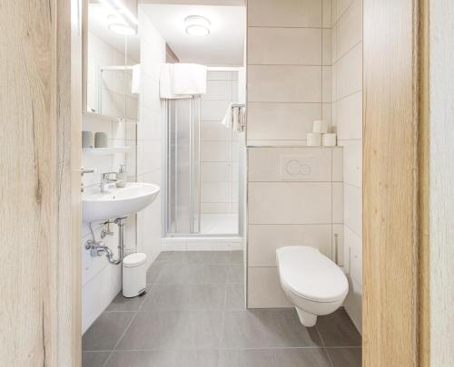 a white bathroom with a toilet and a sink at Weisses Rössl in Pfreimd