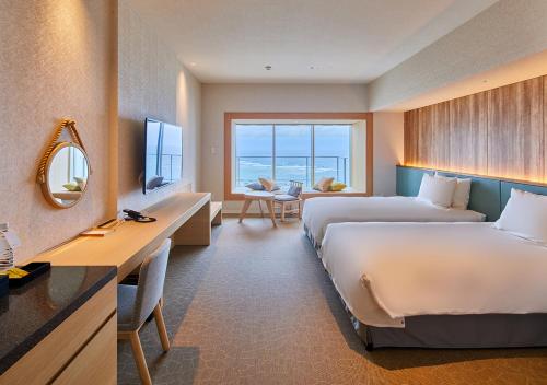 Minatogawaにある ホテルアラクージュオキナワのベッド2台とデスクが備わるホテルルームです。