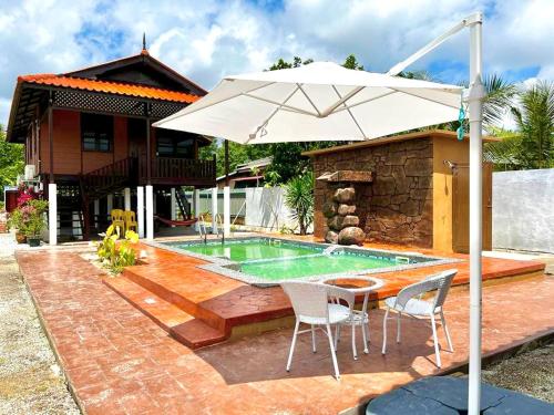 un patio con mesa, sombrilla y piscina en Inap Nekmi Kuala Terengganu With Pool en Kuala Terengganu