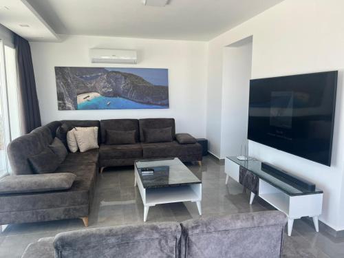 a living room with a couch and a flat screen tv at Courtyard Long Beach Holiday Resort in Iskele