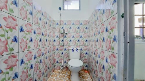 a bathroom with a toilet and flowers on the wall at RedDoorz near Universitas Palangkaraya 3 in Palangkaraya
