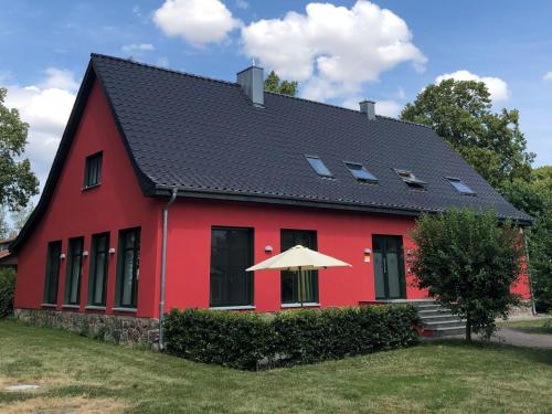 una casa roja con techo negro en Ferienwohnung auf Gut Owstin, en Owstin