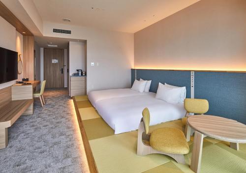 a hotel room with a large bed and a table at HOTEL AlaCOOJU OKINAWA in Urasoe