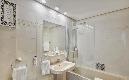 y baño con lavabo, ducha y espejo. en Sercotel Togumar, en Madrid