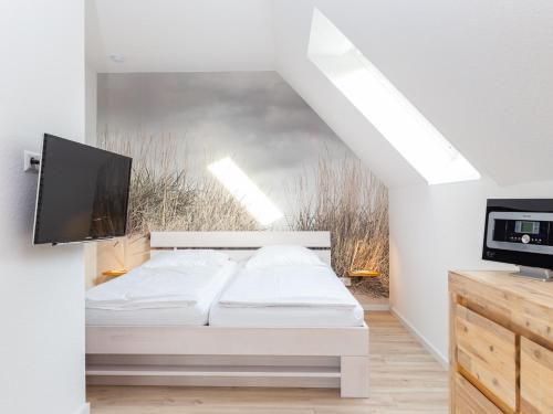 a white bedroom with a bed and a tv at Ferienwohnung 54 Nord in Nebel
