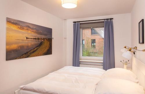 Schlafzimmer mit einem Bett und einem Fenster in der Unterkunft Haus am Seezeichen - Whg. Lürßen in Wittdün