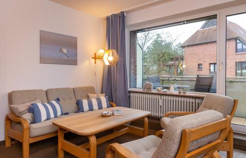 ein Wohnzimmer mit einem Sofa, einem Tisch und einem Fenster in der Unterkunft Haus am Seezeichen - Whg. Lürßen in Wittdün