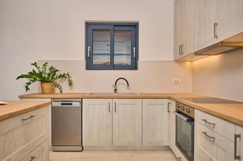 a kitchen with wooden cabinets and a sink and a window at Sea Front Zante Apartments in Zakynthos Town