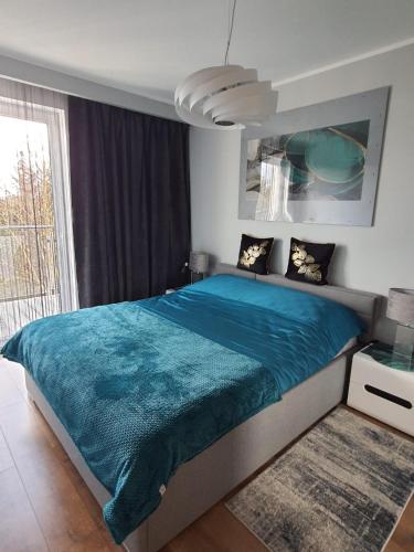a bedroom with a large bed with a blue blanket at Nadmorski Apartament in Gąski