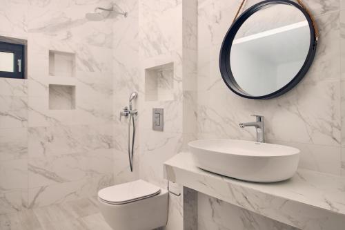 a white bathroom with a sink and a mirror at Sea Front Zante Apartments in Zakynthos Town