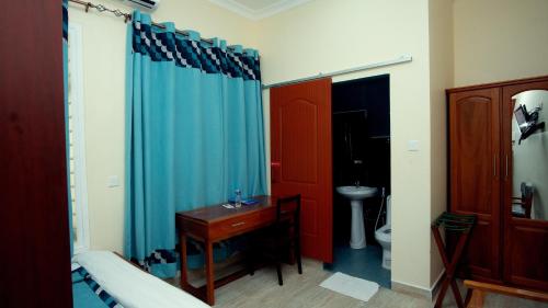 a bathroom with a toilet and a blue shower curtain at La Casa Preciosa in Tanga