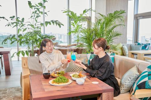 a man and woman sitting at a table eating food at HOTEL AlaCOOJU OKINAWA in Urasoe