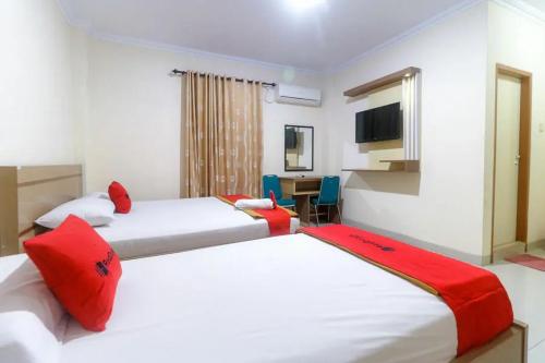 a bedroom with two beds with red pillows and a desk at RedDoorz Plus near WTC Batanghari Mall in Tanjungjohor