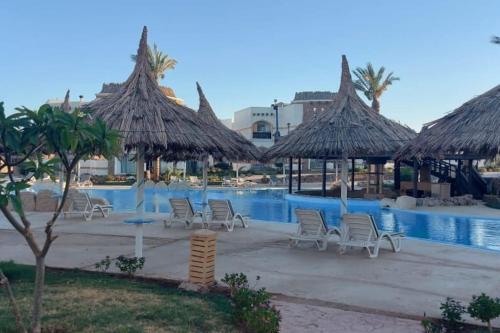 una piscina presso il resort con sedie e ombrelloni di basic 2 bedroom apartment a Sharm El Sheikh