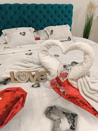 a bed with two heart shaped towels and a wine glass at Stan u centru 1 in Šid