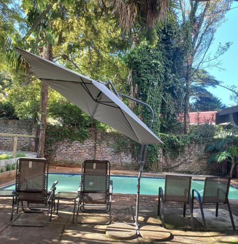 a group of chairs and an umbrella next to a pool at Kruger's Guest House in White River